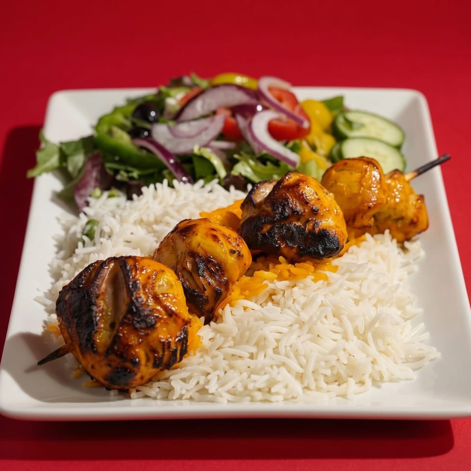 Grilled chicken skewers with white rice and a fresh garden salad on a white plate.